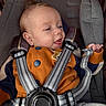 Hayden is registered to the contest to win money with this photo: baby, child, car_seat, safety_harness, orange_sweater, blue_buttons, smiling, happy, infant, clothing, seatbelt, portrait, cute, comfort, indoor, young_child, person, closeup, head, small_hand