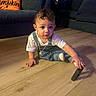 Luis joined the competition — help win amazing prizes! child, toddler, baby, sitting, indoor, living_room, wooden_floor, couch, pillow, pumpkin, autumn, overalls, white_shirt, necklace, curly_hair, face, eyes, curious, portrait, toy