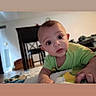baby, infant, child, portrait, face, eyes, curious, lying_down, tummy_time, green_shirt, blanket, bed, indoors, home, dining_chairs, furniture, carpet, daylight, photography, closeup