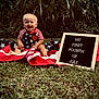 baby, child, grass, american_flag, patriotic, smiling, outdoor, sign, celebration, holiday, clothing, summer, nature, greenery, happy, portrait, sitting, cute, red_white_blue, infant