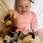 Juliana joined the competition — help win amazing prizes! baby, infant, smile, pink_clothing, ruffled_sleeves, cow_print, headband, bow, plush_toy, triceratops, wooden_sign, four_months, milestone, sitting, white_blanket, happy, cute, portrait, child, indoors