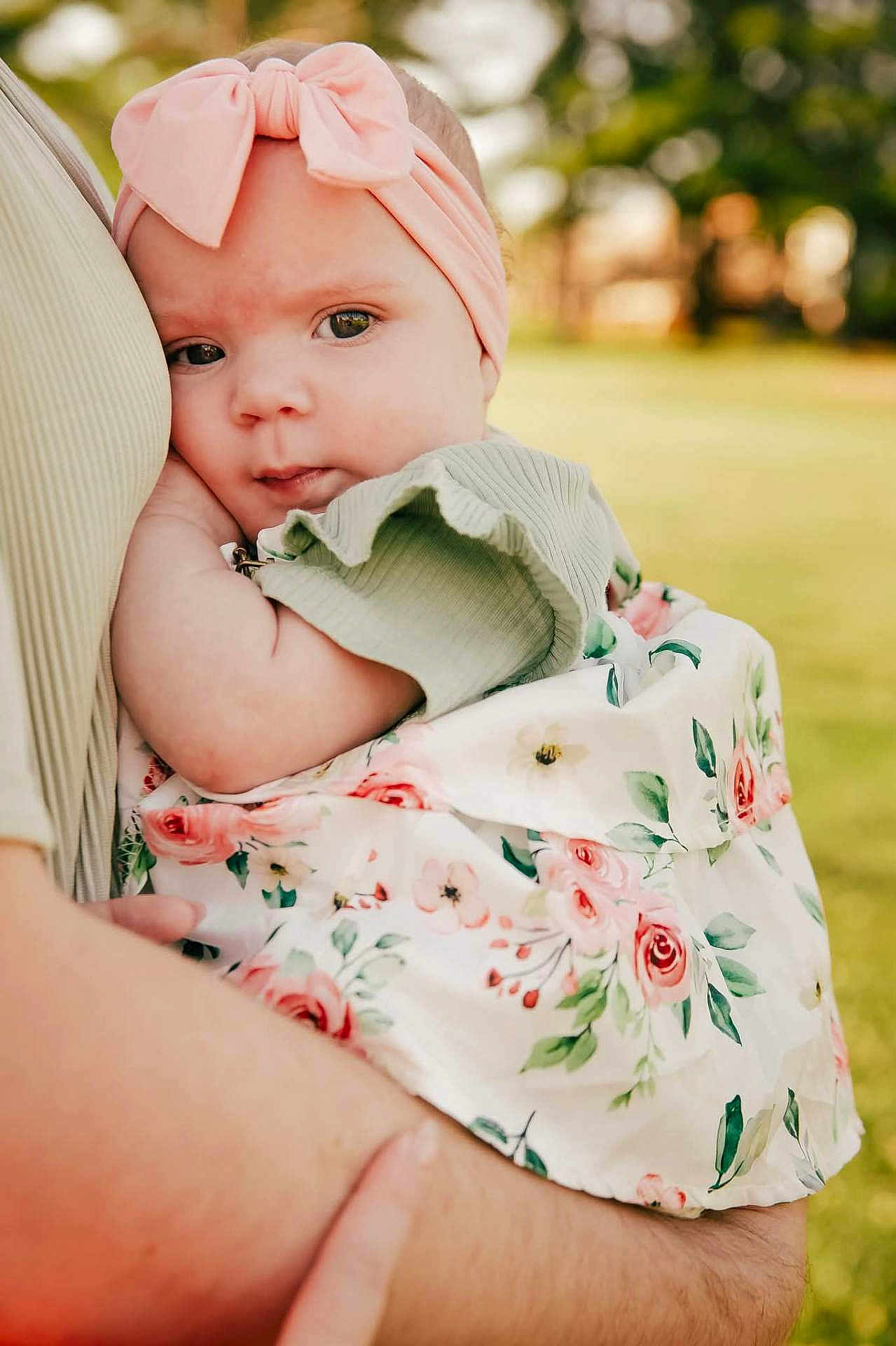 Everleigh joined the competition — help win amazing prizes! baby, child, infant, headband, pink_bow, floral_dress, holding, arm, outdoor, greenery, portrait, cute, person, skin, face, closeup, summer, nature, soft_light, tenderness