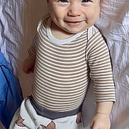 Soam participe au concours pour gagner de l'argent avec cette photo : baby, infant, smiling, striped_shirt, pants, fox_pattern, lying_down, bed, sheet, child, cute, happy, face, person, clothing, indoors, furniture, human, skin, young
