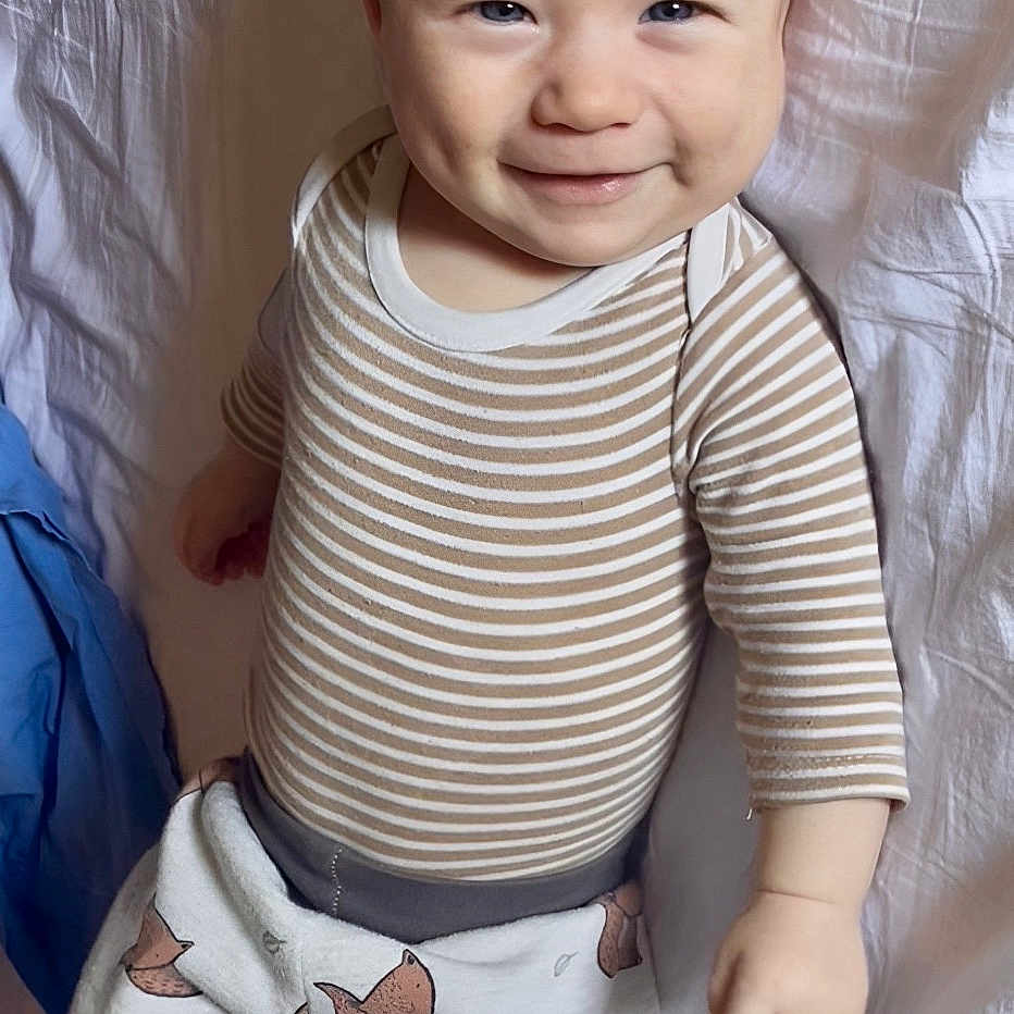 Soam participe au concours pour gagner de l'argent avec cette photo : baby, infant, smiling, striped_shirt, pants, fox_pattern, lying_down, bed, sheet, child, cute, happy, face, person, clothing, indoors, furniture, human, skin, young