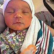 Adeline is registered to the contest to win money with this photo: newborn, baby, sleeping, hat, blanket, floral_clothing, pacifier, hospital, closeup, face, peaceful, infant, person, soft_lighting, wrapped, cute, child, indoors, portrait, resting