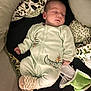 baby, sleeping, infant, onesie, cushion, blanket, pattern, dinosaur_print, sock, checkered, cozy, soft, indoor, resting, peaceful, child, person, cute, nursery, comfortable
