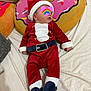 Elio participe au concours pour gagner de l'argent avec cette photo : baby, infant, santa_outfit, holiday_costume, sleeping, bed, pillow, donut_pillow, plush, red_clothing, white_trim, black_belt, footed_pajamas, soft_texture, indoors, cute, child, festive, holiday, resting