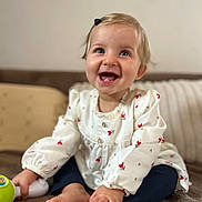 Giulia a rejoint le concours — aidez-le/la à gagner de superbes lots ! baby, child, smiling, happy, sitting, barefoot, toy, hair_clip, long_sleeve_shirt, patterned_clothing, blue_eyes, indoor, blanket, cushion, cozy, portrait, cute, infant, person, home