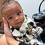 baby, infant, child, person, hand, clothing, mickey_mouse, minnie_mouse, pattern, leopard_print, face, eyes, expression, indoor, furniture, car_seat, cute, closeup, portrait, holding