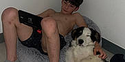 Balky a rejoint le concours — aidez-le/la à gagner de superbes lots ! boy, dog, bean_bag, nintendo_switch, indoor, floor, casual, relaxed, pet, companion, shorts, socks, light_skin, black_hair, white_wall, wooden_floor, playing, technology, comfort, resting