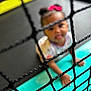Harmony is registered to the contest to win money with this photo: child, toddler, net, blur, indoor, crawling, pink_bow, colorful, play_area, black_net, floor, padded_surface, young_child, baby, curious, playful, person, headwear, clothing, hands