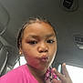 child, girl, selfie, pink_shirt, beaded_necklace, peace_sign, car_interior, seat, earrings, portrait, closeup, braided_hair, playful, expression, casual, window, lighting, young, person, fun