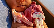 Dream is registered to the contest to win money with this photo: newborn, baby, sleeping, infant, portrait, pink_clothing, pacifier, pacifier_clip, floral_design, adult_arm, cuddling, close_up, warm_lighting, sunlight, indoor, cozy, peaceful, child, face, hands