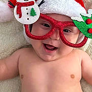 Thiago joined the competition — help win amazing prizes! baby, smiling, santa_hat, glasses, snowman, holiday, christmas, festive, red, green, diaper, cute, infant, happy, lying_down, soft_blanket, celebration, face, headwear, portrait