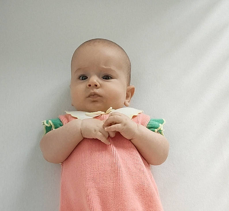 Lili a rejoint le concours — aidez-le/la à gagner de superbes lots ! arm, baby, baby_toddler_clothing, cheek, day_dress, dress, eye, finger, gesture, hand, happy, human_body, iris, lip, neck, one_piece_garment, person, skin, sleeve, thumb