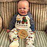 baby, child, clothing, cozy, cute, face, farm_theme, five_months, footwear, happy, indoors, infant, pajamas, person, plush_chair, portrait, sitting, smiling, soft_texture, wooden_sign
