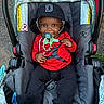 Dedrick joined the competition — help win amazing prizes! baby, infant, child, stroller, pacifier, hat, bucket_hat, red_shirt, black_pants, socks, smiling, portrait, outdoors, seated, car_seat, safety_harness, canopy, patterned_fabric, playful, happy