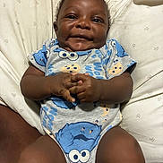 Dedrick joined the competition — help win amazing prizes! baby, infant, child, portrait, smiling, happy, lying_down, bed, pillow, blanket, onesie, clothing, blue, patterned, remote_control, indoor, bedroom, face, hands, photograph