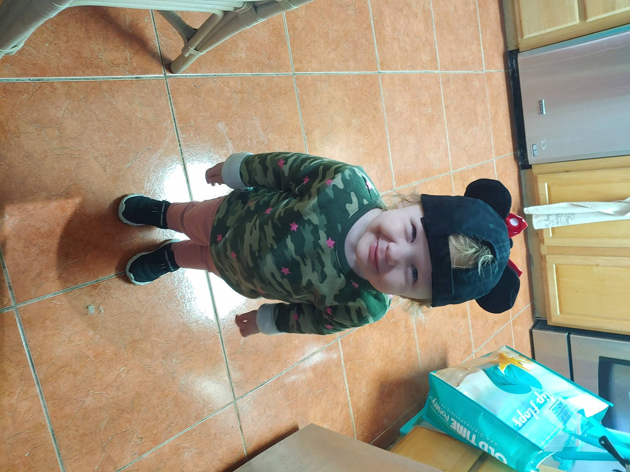 Yelena is registered to the contest to win money with this photo: box, cardboard, floor, flooring, headwear, joy, outdoor_shoe, person, shipping_box, shoe, slipper, tile, walking_shoe