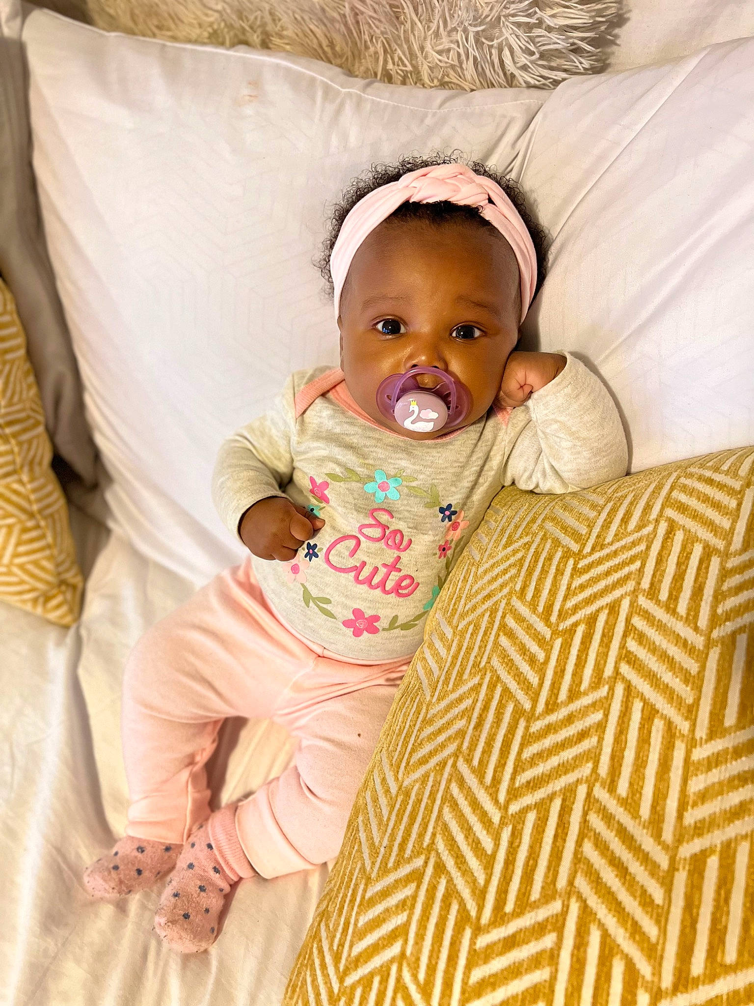 Anaya is registered to the contest to win money with this photo: baby, baby_toddler_clothing, bedding, cheek, clothing, comfort, couch, eye, face, flooring, happy, head, linens, person, product, sitting, skin, sleeve, textile, toddler