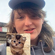 Noah is registered to the contest to win money with this photo: animal, cap, casual, cat, cute, digital_insertion, fluffy, fur, hair, hoodie, kitten, outdoor, person, portrait, selfie, sky, small, smile, wide_eyes, young