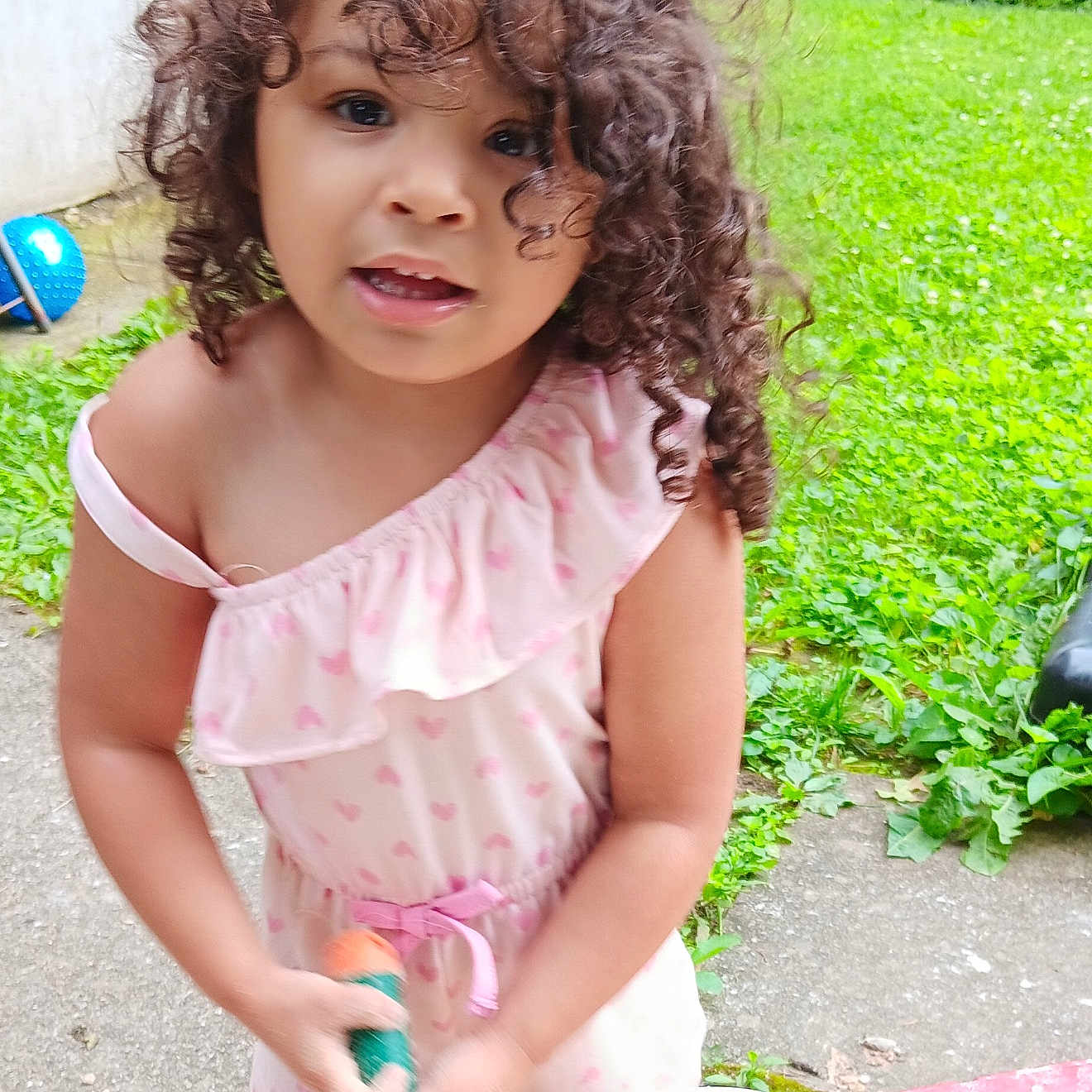 Amani joined the competition — help win amazing prizes! child, concrete_path, curly_hair, cute, daylight, garden, grass, greenery, nature, outdoor, person, pink_dress, playing, portrait, sand, shovel, summer, toddler, toy, young_child