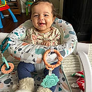 Korra joined the competition — help win amazing prizes! baby, infant, child, smile, smiling, baby_seat, teether, toy, booties, onesie, patterned_fabric, play_mat, indoor, living_room, wood_floor, blanket, happy, hair_ties, portrait, face