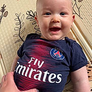 Marin participe au concours pour gagner de l'argent avec cette photo : baby, blue_shirt, child, cute, expression, face, grey_pants, hand, happy, indoor, infant, logo, lying_down, patterned_mat, person, shirt, skin, small_hand, smiling, tshirt