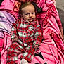 Romy participe au concours pour gagner de l'argent avec cette photo : baby, infant, plaid_pajamas, red, white, blanket, pink, socks, face, portrait, indoors, cute, child, clothing, person, resting, soft, fabric, couch, expression