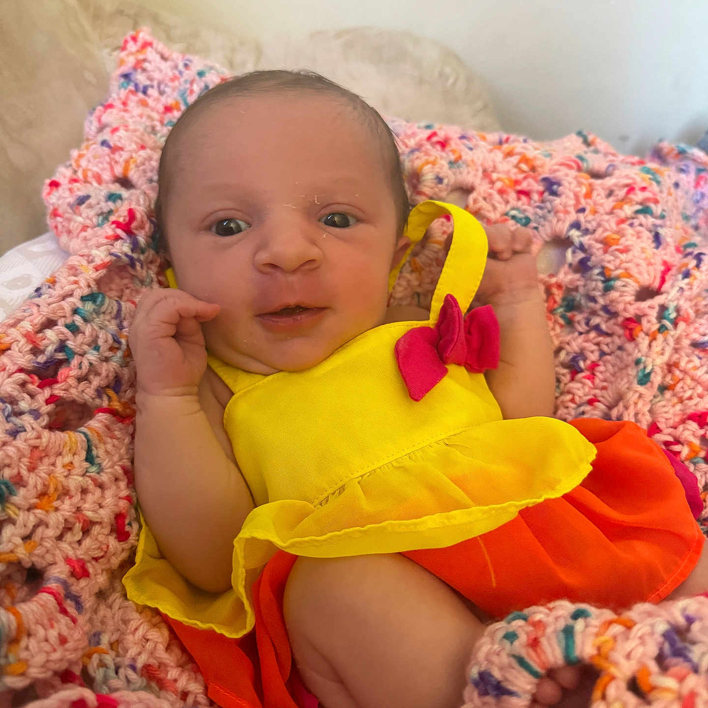 Hailey joined the competition — help win amazing prizes! baby, blanket, clothing, colorful, cozy, crochet, cute, dress, fabric, face, hand, infant, lying_down, newborn, orange, person, portrait, soft, texture, yellow