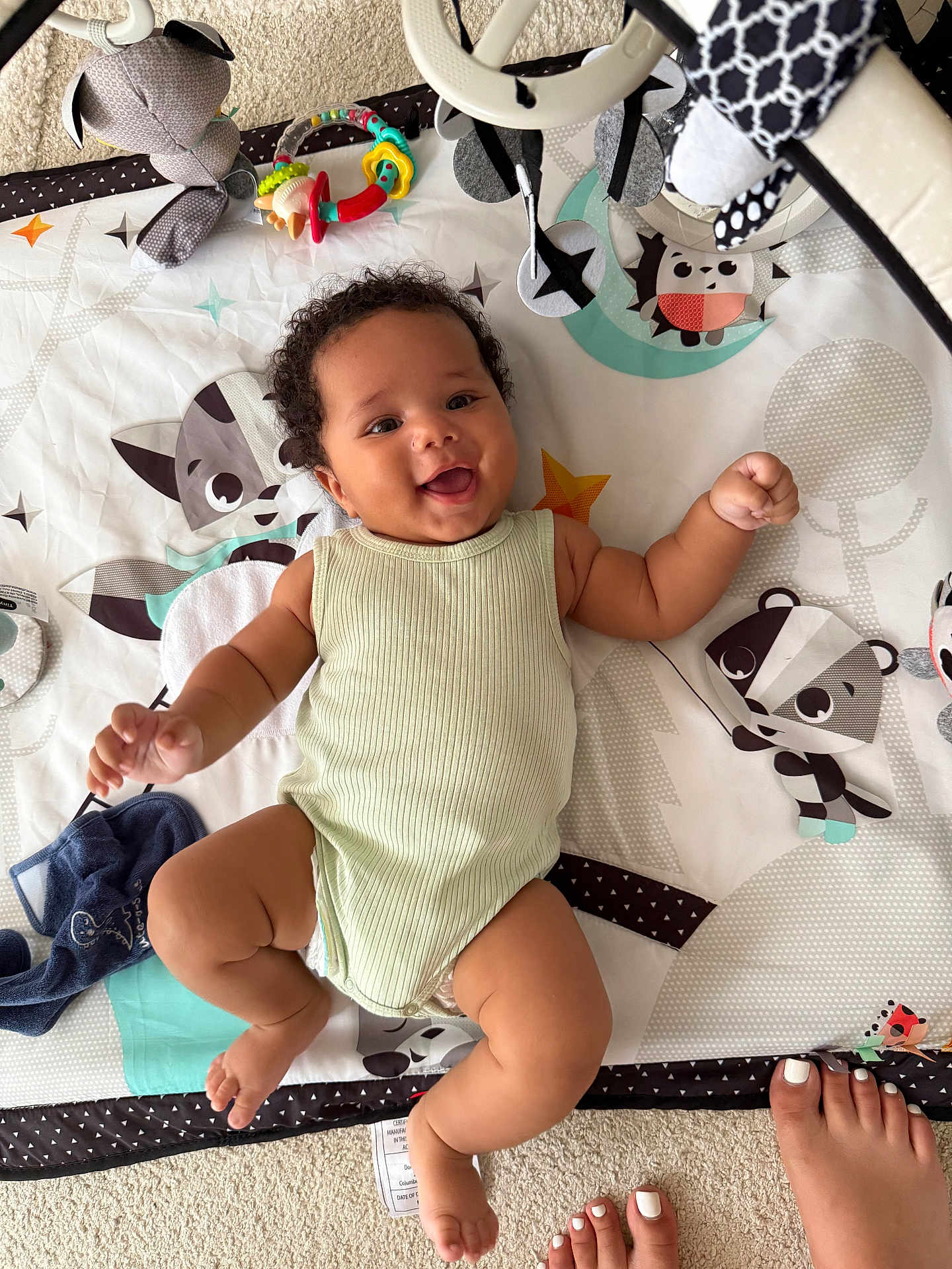 Aïnis participe au concours pour gagner de l'argent avec cette photo : baby, smiling, play_mat, animal_patterns, infant, happy, child, carpet, toes, nail_polish, cute, indoors, clothing, sleeveless_onesie, chubby_arms, chubby_legs, toy, colorful, lying_down, soft