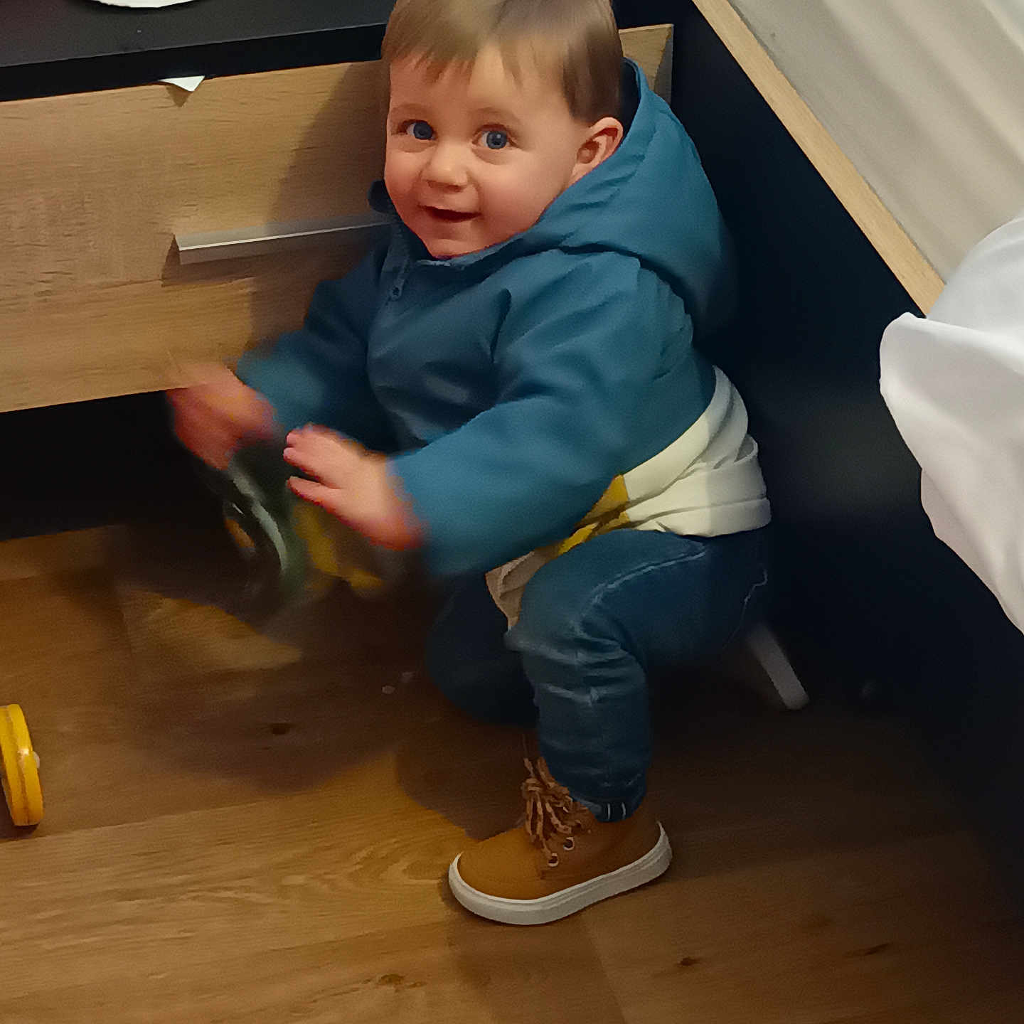 Taho participe au concours pour gagner de l'argent avec cette photo : bed, blue_jacket, brown_boots, child, clothing, curious, drawer, furniture, hair, happy, indoor, motion_blur, person, playing, smile, squatting, toddler, toy, wooden_floor, young_child