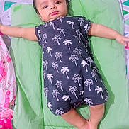 Parth joined the competition — help win amazing prizes! baby, infant, lying_down, romper, palm_tree_pattern, green_cushion, bed, colorful_bedding, child, cute, indoors, sleepwear, person, small_child, soft_lighting, relaxed, skin, foot, hand, head