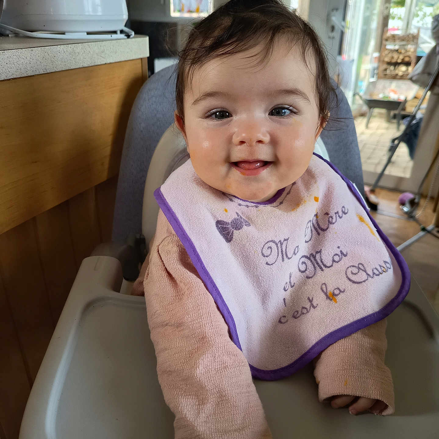 Anita participe au concours pour gagner de l'argent avec cette photo : baby, bib, child, cozy, face, feeding, hair, happy, high_chair, indoors, infant, kitchen, long_sleeve, messy_face, person, pink_clothing, smile, sunlight, window, wooden_cabinet