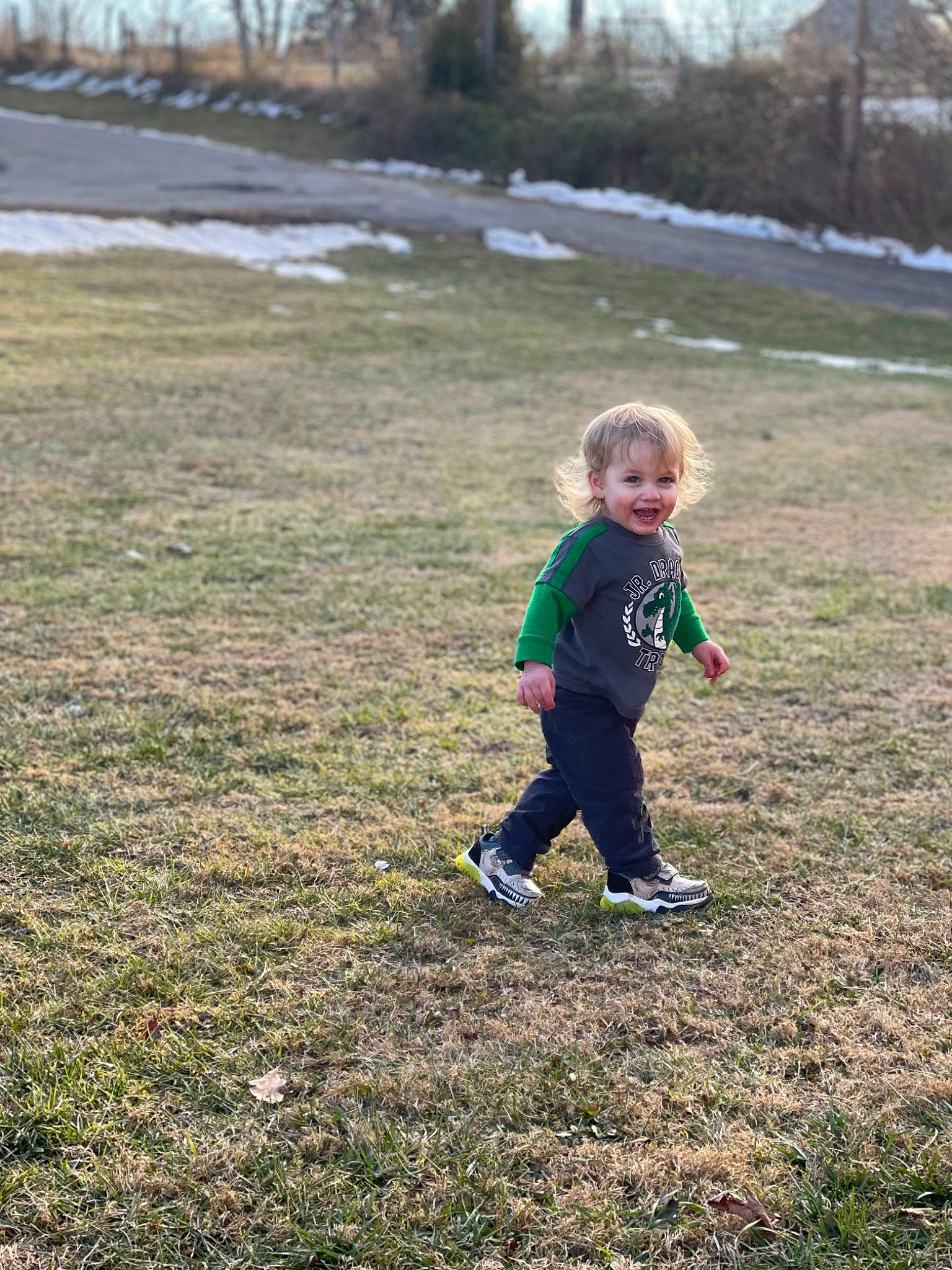 Finnegan is registered to the contest to win money with this photo: asphalt, child, fun, grass, grass_family, grassland, landscape, lawn, natural_environment, people_in_nature, person, plain, plant, play, recreation, smile, snow, soil, toddler, tree
