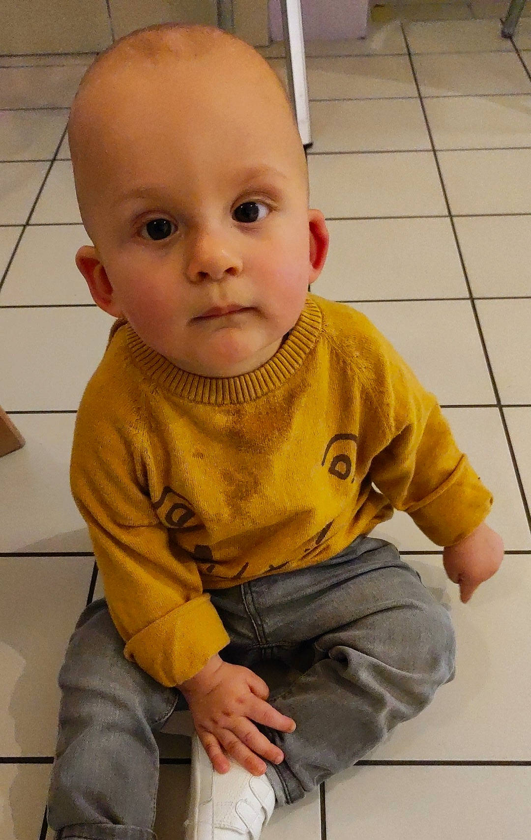 Jules participe au concours pour gagner de l'argent avec cette photo : baby, baby_toddler_clothing, cheek, child, denim, eye, finger, floor, flooring, fun, joint, nose, pattern, person, sitting, skin, sleeve, standing, t_shirt, toddler
