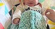 Dawson is registered to the contest to win money with this photo: baby, smile, blanket, cushion, patterned, colorful, hand, infant, clothing, face, happy, seated, indoors, cozy, soft, cute, child, portrait, person, fabric
