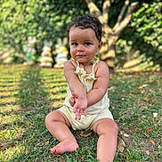 Naïa a rejoint le concours — aidez-le/la à gagner de superbes lots ! barefoot, bunny_decor, child, curly_hair, cute, daylight, garden, grass, greenery, nature, outdoor, person, playful, portrait, sitting, summer, sunlight, toddler, tree, yellow_outfit