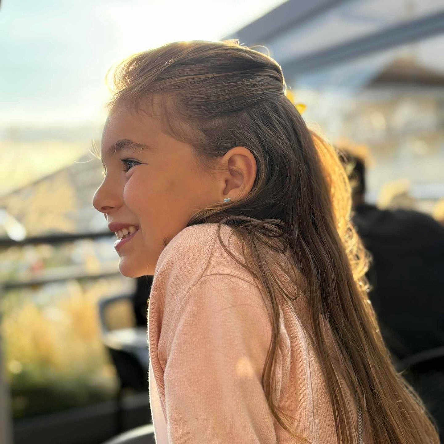 Lou a rejoint le concours — aidez-le/la à gagner de superbes lots ! backlit, casual, child, daylight, earring, girl, happy, long_hair, natural_light, outdoor, person, portrait, profile, relaxed, side_view, smiling, sunlight, sweater, warm, young