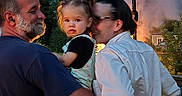 Elliana is registered to the contest to win money with this photo: child, toddler, man, woman, outdoor, family, holding, smoke, trees, nature, evening, casual_clothing, glasses, beard, portrait, curious, greenery, light, people, backdrop
