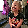 Elliana is registered to the contest to win money with this photo: toddler, child, smiling, happy, indoor, fan, exercise_equipment, jacket, carpet, black_shirt, colorful_print, hair, person, room, toy, holding, laughing, face, young_child, cute