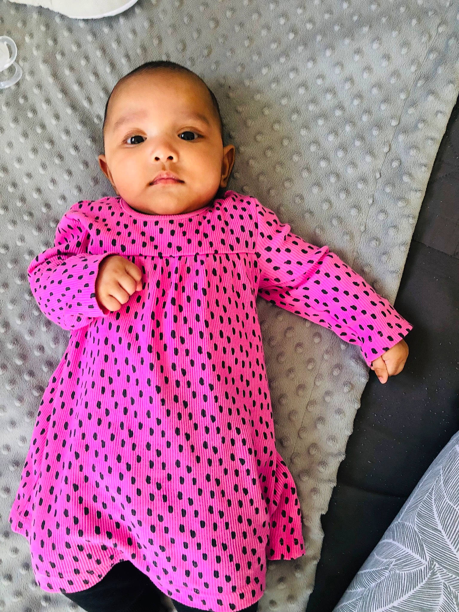 Aisha is registered to the contest to win money with this photo: arm, baby, baby_products, baby_toddler_clothing, child, dress, face, facial_expression, happy, head, human_body, linens, magenta, neck, outerwear, pattern, person, pink, skin, sleeve