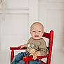 baby, blue_eyes, bright, casual_clothing, child, cozy, cute, happy, indoor, infant, jeans, portrait, red_chair, seated, smile, sweatshirt, toddler, toothy_grin, white_background, wooden_chair