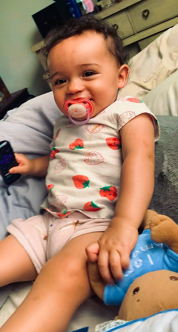 Gabrielle is registered to the contest to win money with this photo: baby, baby_toddler_clothing, cheek, child, comfort, eye, face, finger, fun, happy, head, iris, mouth, nose, organ, person, skin, smile, thigh, toddler