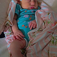 Olivia is registered to the contest to win money with this photo: baby, infant, sleeping, bow, blanket, onesie, floral_pattern, cushion, pink, blue, hand, foot, face, peaceful, resting, soft_texture, indoor, person, child, newborn