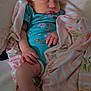 baby, infant, sleeping, bow, blanket, onesie, floral_pattern, cushion, pink, blue, hand, foot, face, peaceful, resting, soft_texture, indoor, person, child, newborn