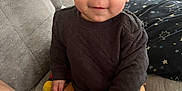 Kaine joined the competition — help win amazing prizes! baby, child, smiling, sitting, couch, clothing, pants, sweater, face, hand, foot, dinosaur_print, indoor, home, cushion, blanket, person, cute, infant, cozy