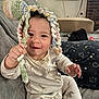 Kaine joined the competition — help win amazing prizes! baby, child, onesie, crocheted_hat, couch, blanket, pillow, indoor, smiling, happy, playful, cute, infant, soft_furniture, animal_print, hand, face, headwear, relaxed, cozy