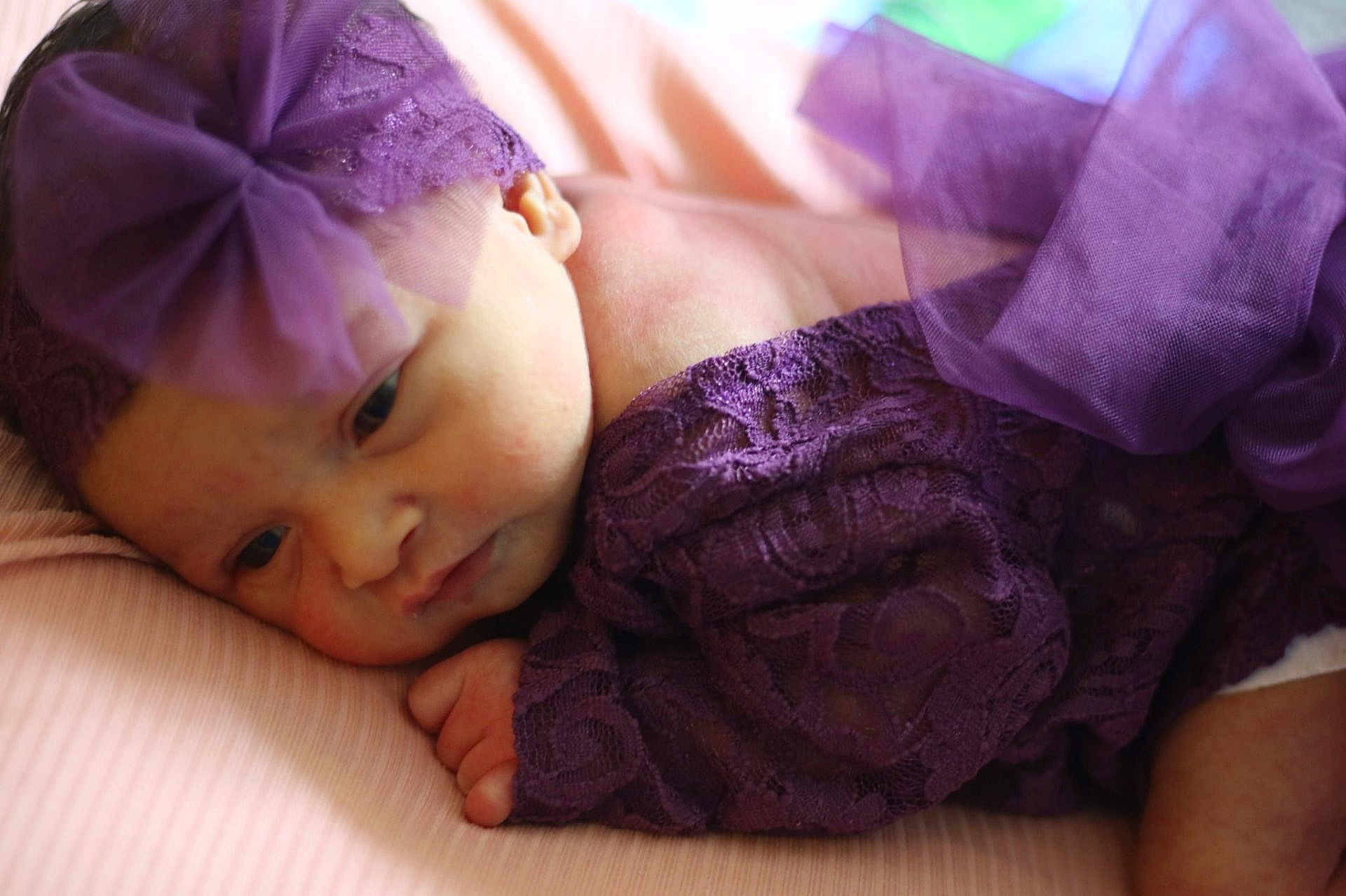 Ivy is registered to the contest to win money with this photo: baby, newborn, infant, purple_lace, headband, sleeping, soft, closeup, portrait, cute, delicate, resting, pink_background, child, small_hand, peaceful, fabric, texture, face, skin