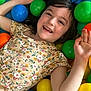 ball_pit, casual, child, childhood, colorful, cute, floral_dress, fun, girl, hair, happy, indoor, joy, leisure, plastic_balls, playful, portrait, relaxing, skin, smiling